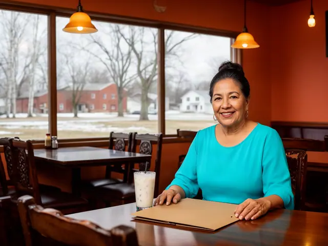 A smiling restaurant owner in turquoise seated with a folder and horchata in her dining room.